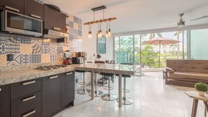 Une cuisine moderne dotée d’un grand îlot central, de meubles de couleur sombre et d’un revêtement mural décoratif.