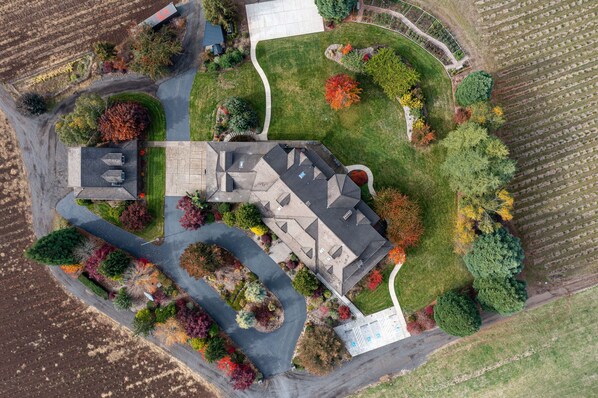 Vue aérienne d’une propriété résidentielle comprenant une maison, une allée et un jardin aménagé.