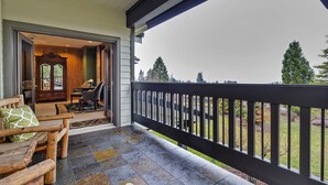 A covered porch with a view of a yard and trees.