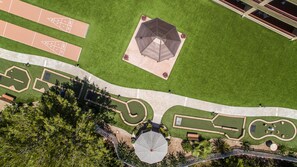 Vue aérienne d’un parc avec un kiosque central, des sentiers pédestres et un terrain de sport.