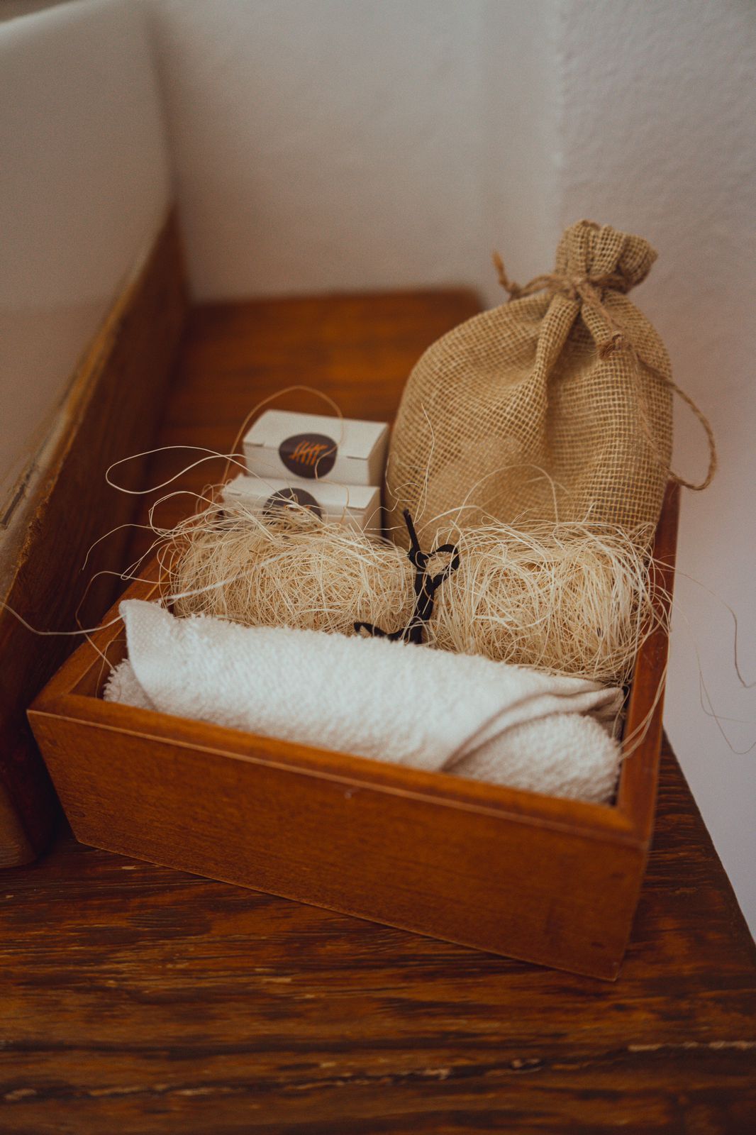 A wooden box containing a burlap sack, a white cloth, and some twine.