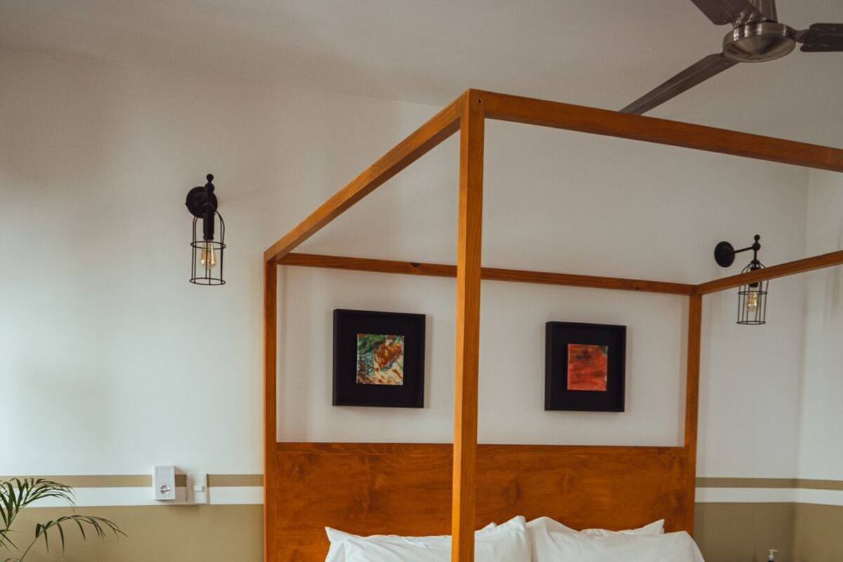 Ein Bett mit Himmel und Holzrahmen, dazu ein Nachttisch mit Lampe und ein fußbodenmuster.