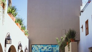 Ein Innenhof mit einer großen blauen Wandmalerei, Blumentöpfen und Gartenmöbeln.