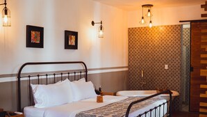 Ein Schlafzimmer mit Bett, Schreibtisch, Stuhl, Deckenventilator und ornamentalem Wandpapier.