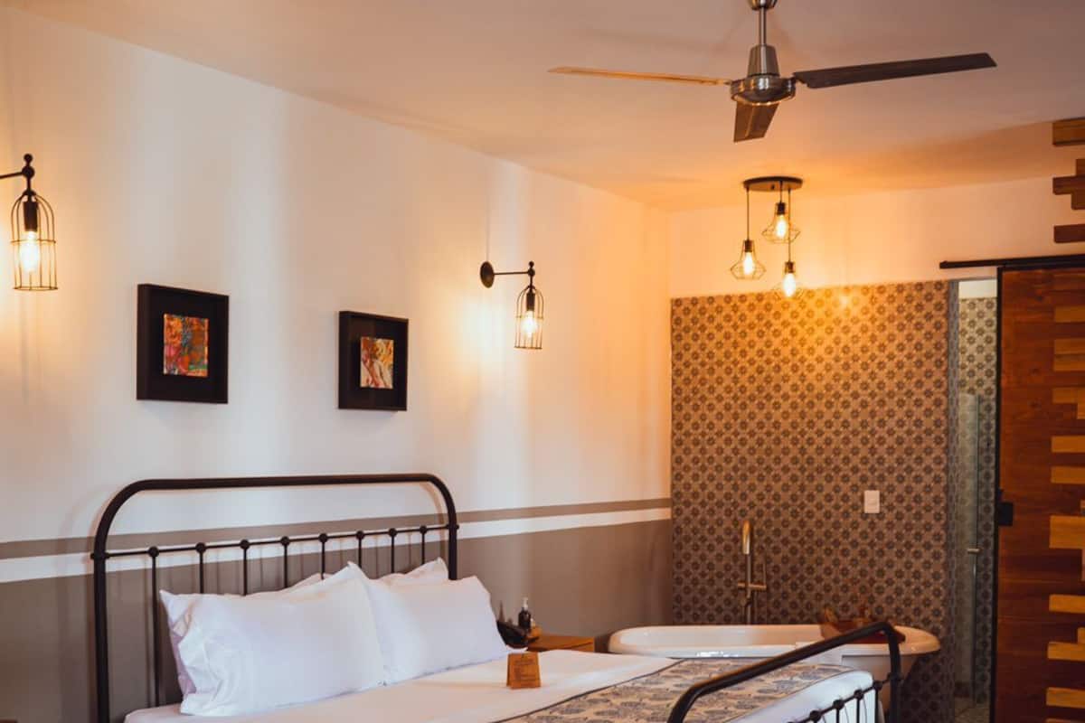 Ein Schlafzimmer mit Bett, Schreibtisch, Stuhl, Deckenventilator und ornamentalem Wandpapier.