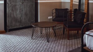 Ein Zimmer mit großem Kleiderschrank, kleinem runden Tisch, einer Couch und einem Spiegel an der Wand.