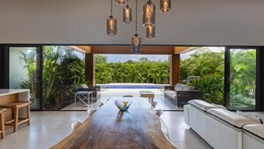Uma sala de jantar moderna com uma mesa de madeira, cadeiras brancas e uma mesa de centro com tampo de vidro.