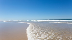 Une plage avec un ciel dégagé et des vagues douces.