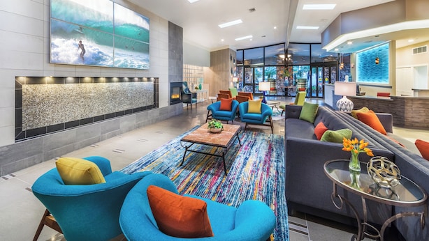 A modern lobby with a large wall mural, comfortable seating, a fireplace, and a reception area. - 1 Bedroom/1 Bathroom Sleep 4 SC (San Clemente)
