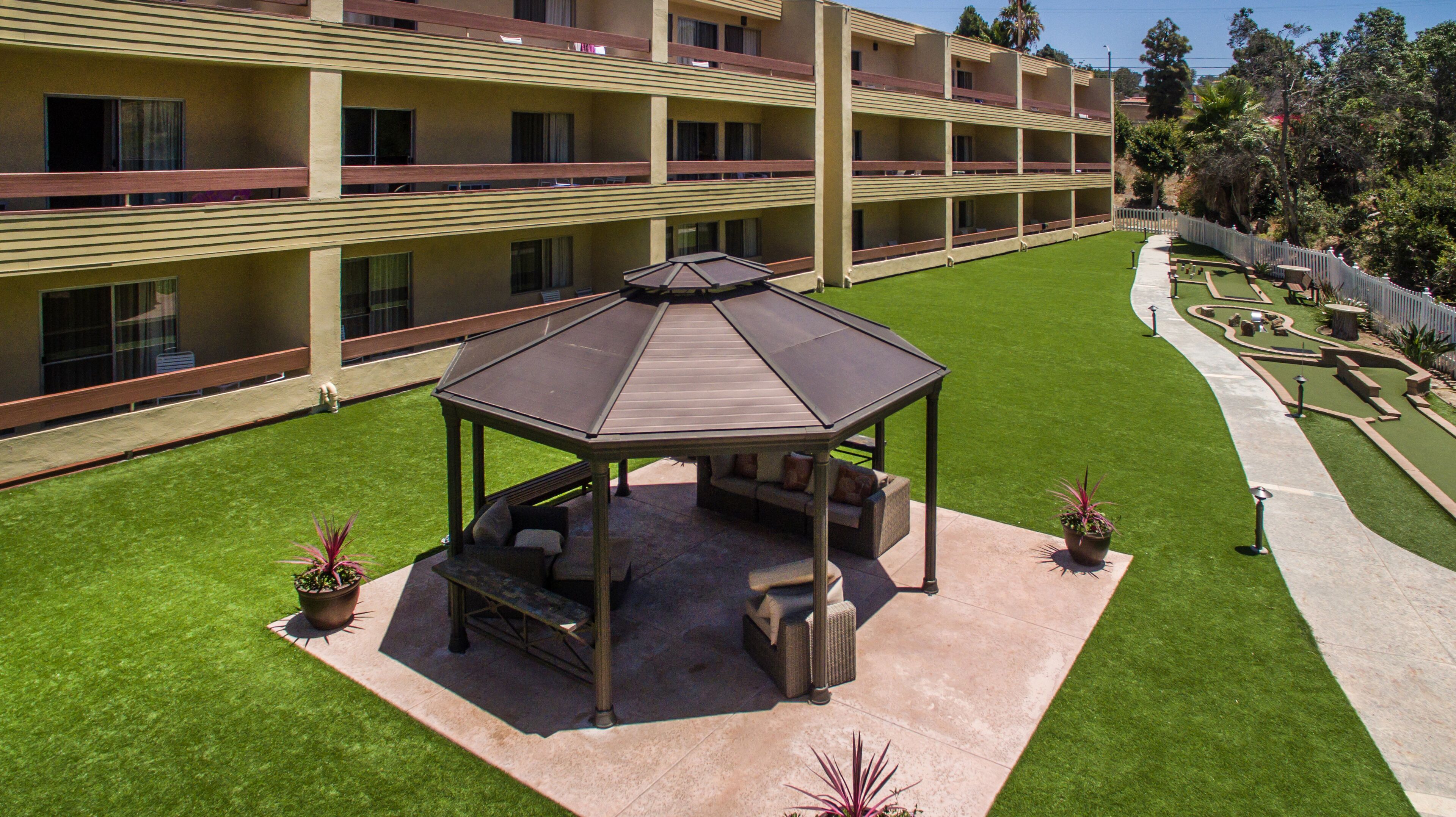 Un hôtel à plusieurs étages doté d’un jardin sur le toit comprenant un belvédère, des espaces de détente en plein air et une pelouse bien entretenue.