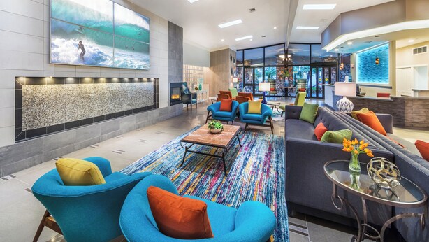 A modern lobby with a large wall mural, comfortable seating, a fireplace, and a reception area. - 1 Bedroom/1 Bathroom Sleep 4 SC (San Clemente)