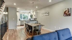 A modern kitchen with white cabinets, a dining table with chairs, and a sign on the wall reading "GROCERY." - Private Elevator in Hot South Slope (Asheville)