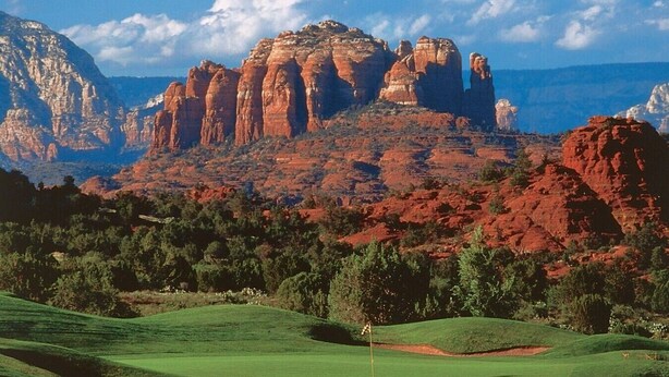 A golf course with a flagstick, surrounded by red rock formations and green trees. - 10 Min-Buddha Beach- Oak Creek | Pet & RV Friendly (Sedona)