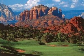 A golf course with a flagstick, surrounded by red rock formations and green trees. - 10 Min-Buddha Beach- Oak Creek | Pet & RV Friendly (Sedona)
