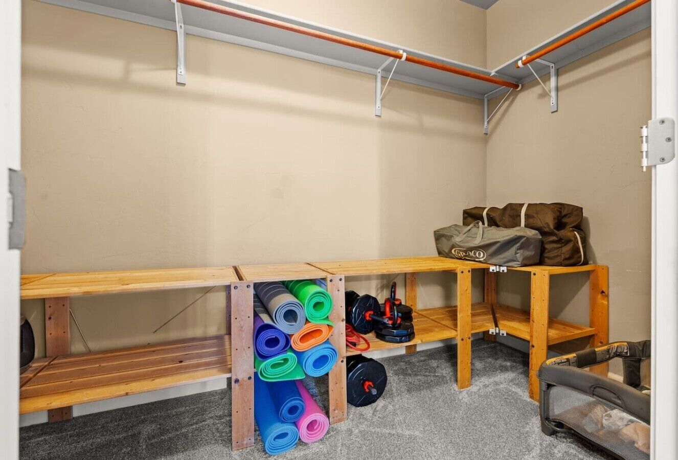 Een sportschool met houten banken, een rek met kleurrijke matten en een plank met tassen en gewichten.