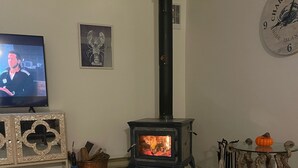 Een woonkamer met een open haard, een televisie en een klok aan de muur.