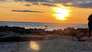 Een strand met rotsen en een zonsondergang.