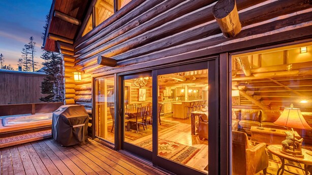 Een vakantiehuis van hout met een terras, een overdekte barbecue en een eethoek met stoelen en een tafel.