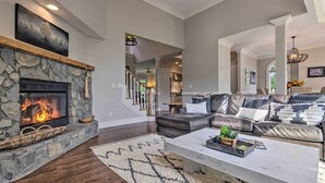 A spacious living room with a stone fireplace, leather sofa, and a large coffee table. - Spacious Elk Mountain Sanctuary w/ Deck & Views! (Asheville)