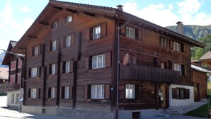 A multi-story wooden building with a sloped roof, multiple windows, and a balcony.