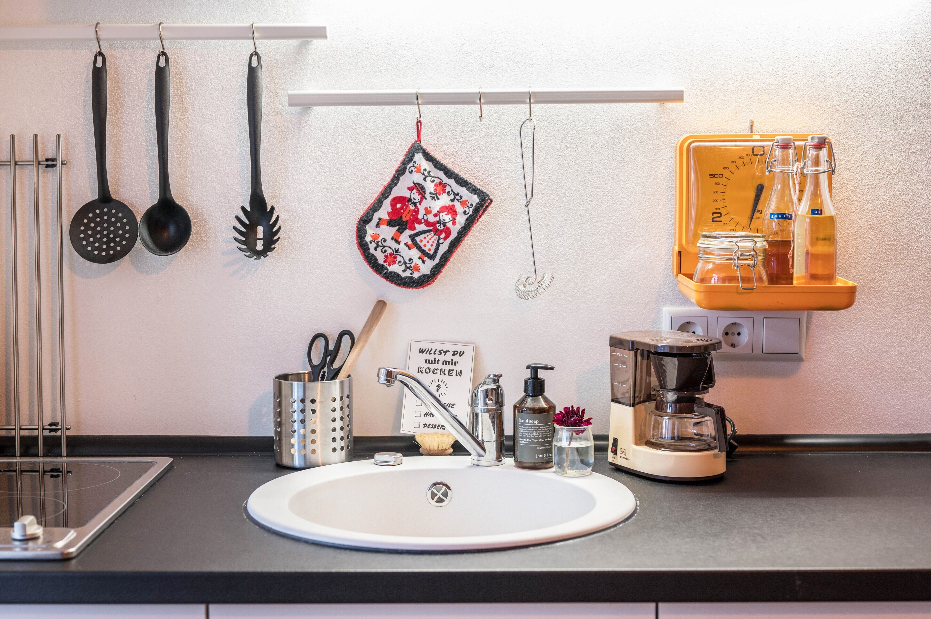 A kitchen with a sink, a coffee maker, and various utensils.