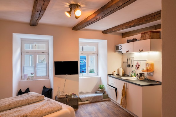 Une chambre à coucher avec un lit, une table de chevet, une fenêtre et une vue sur l’extérieur.