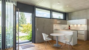 A modern kitchen with a central island, white cabinetry, and a view of greenery outside.