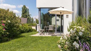 A modern house with a glass door patio, a table, and chairs.