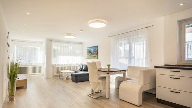 A modern living room with a dining area, a sofa, a coffee table, and a kitchen counter.