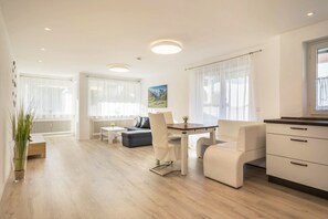 Ein modernes Wohnzimmer mit Essbereich, einer Couch, einem Couchtisch und einer Küchenzeile.