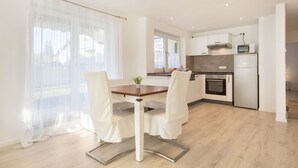 A modern kitchen with white cabinets, a built-in oven, and a microwave.