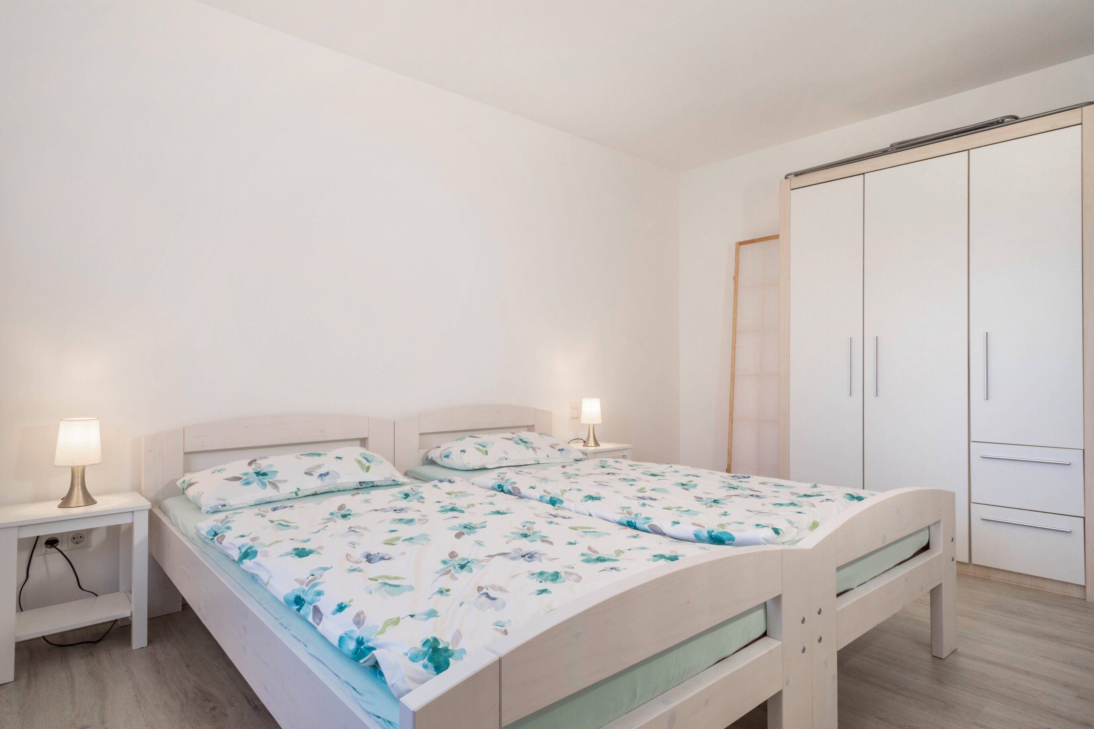 Une chambre à coucher avec un lit, des tables de chevet et une armoire.