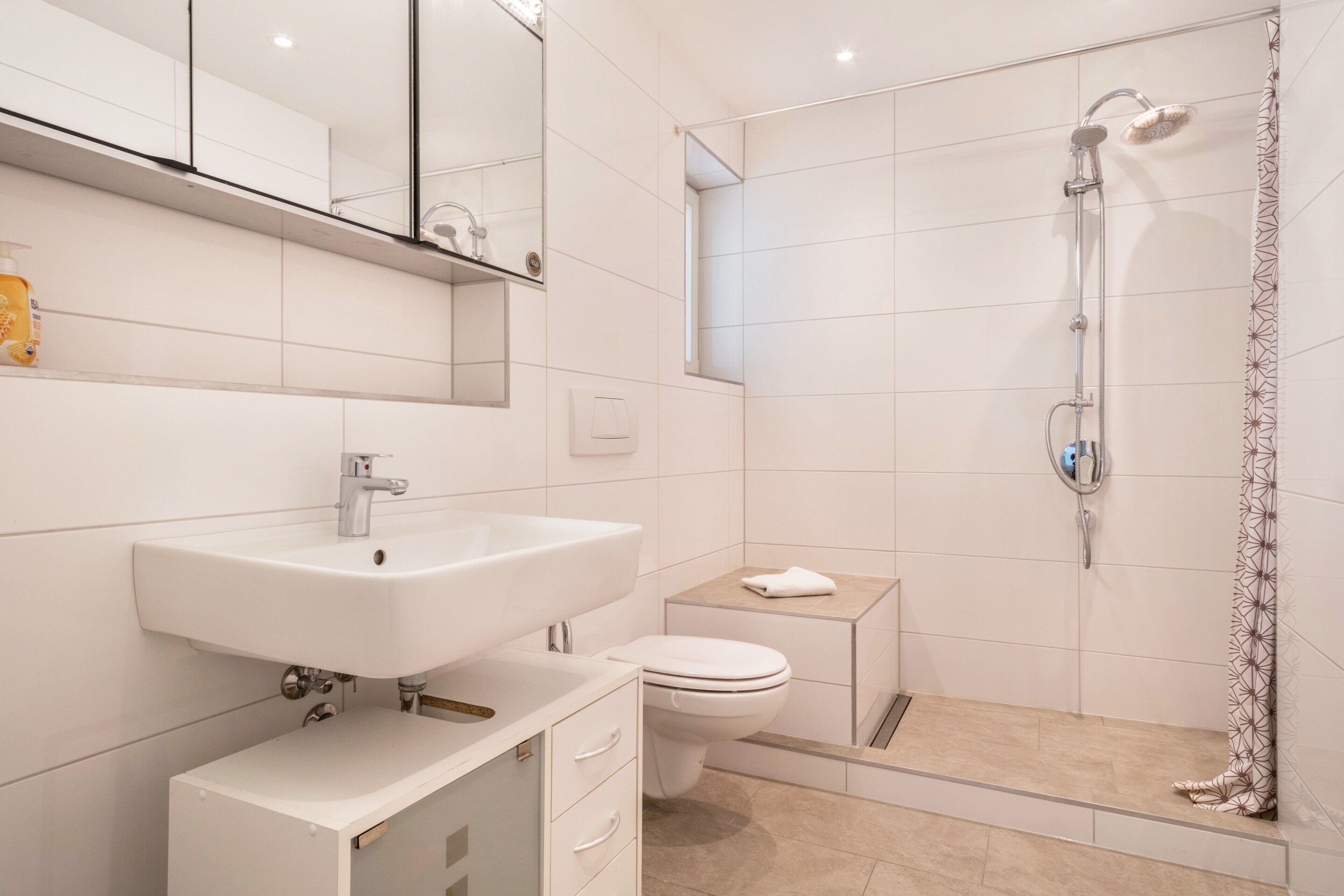A modern bathroom with a sink, toilet, and shower.