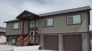 A two-story house with a front porch, a garage, and a staircase leading to the second floor. - Ark Valley BV Home New Construction STR-108 (Buena Vista)
