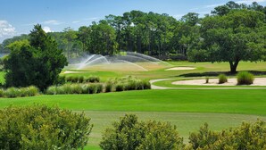 Un parcours de golf agrémenté d’un plan d’eau, de bunkers de sable et d’une végétation luxuriante.