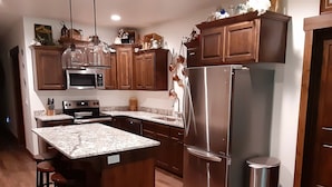 Una cocina moderna con armarios de madera, electrodomésticos de acero inoxidable y una encimera de granito.