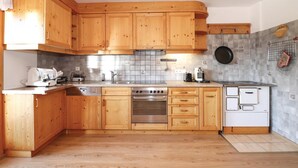 A kitchen with wooden cabinets, a stainless steel stove, a dishwasher, and a small refrigerator. - großes Ferienhaus St. Sigmund (Sankt Sigmund)