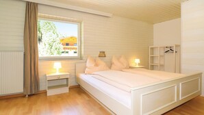 A bedroom with a bed, bedside tables, a hanging wardrobe, and a window with a view of a building. - großes Ferienhaus St. Sigmund (Sankt Sigmund)