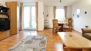 A living room with a TV, wooden furniture, a dining table, and a sofa. - Sünnslag Whg. Sü5/118 (Ostseebad Boltenhagen)