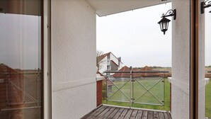A wooden deck with a glass door leading to a grassy yard. - Sünnslag Whg. Sü5/118 (Ostseebad Boltenhagen)