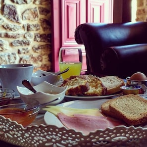 Une table mise pour le petit-déjeuner avec du pain, du jambon, des œufs et un verre de jus de fruits.