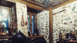 A cozy room with a stone wall, a leather sofa, a wooden coffee table, and a chandelier.