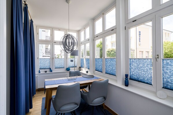 A dining area with a table, chairs, and a view of a hotel building through large windows.