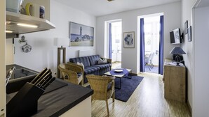 Een moderne woonkamer met een bank, stoelen, een eethoek en een keuken met keukengerei.