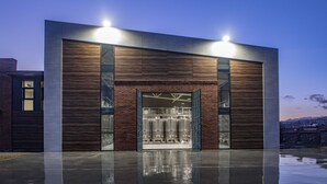 A modern building with a large glass entrance, a brick facade, and a metal structure inside. - Villa Mosavali (Mtskheta)