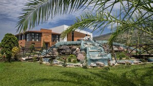 A modern building with a brick facade, a landscaped garden with a water feature, and a palm tree. - Villa Mosavali (Mtskheta)