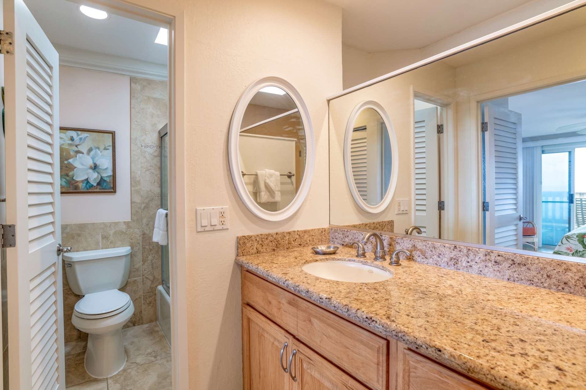 A bathroom with a double sink, a toilet, and a large mirror.
