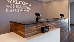 Een receptiebalie met een houten paneelontwerp en een bord met daarop 'Welcome to the Heartland Province'.