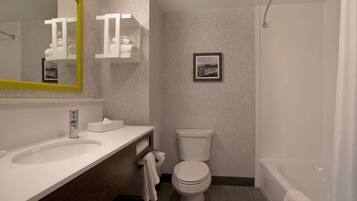 A modern bathroom with a large mirror, a sink, a toilet, and a bathtub.
