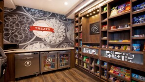 Een zithoek met een muurschildering, een gekoelde vitrine voor snacks en een magnetron.